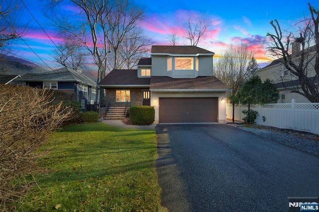 traditional home with driveway, a garage, fence, and a yard