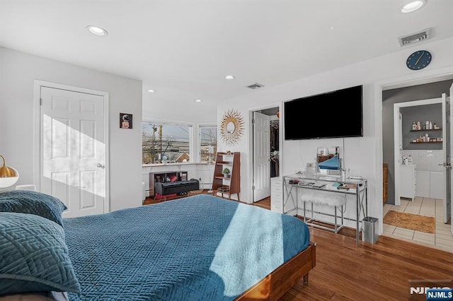 bedroom with a spacious closet, visible vents, wood finished floors, and recessed lighting