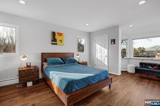 bedroom with baseboards, a baseboard heating unit, wood finished floors, and recessed lighting