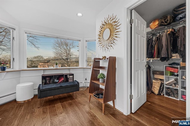 living area featuring baseboard heating, wood finished floors, and recessed lighting