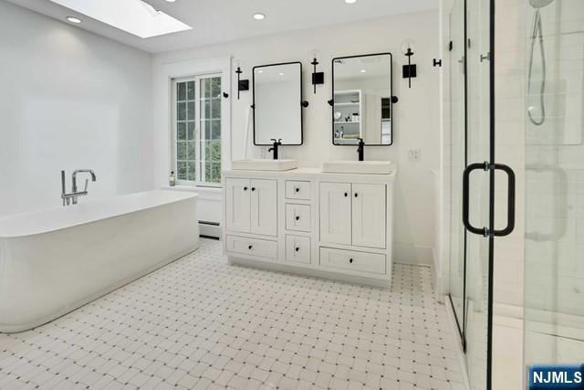 full bathroom with a stall shower, a skylight, a sink, and a baseboard radiator