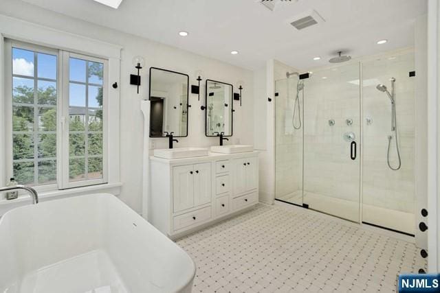 bathroom with a stall shower, a freestanding tub, a sink, and double vanity