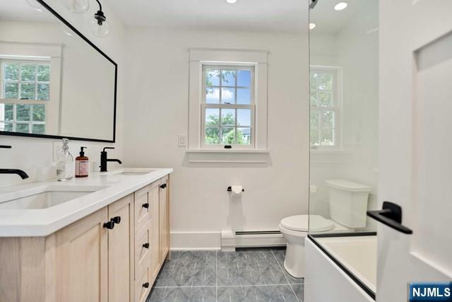 bathroom featuring plenty of natural light, a baseboard radiator, a sink, and toilet