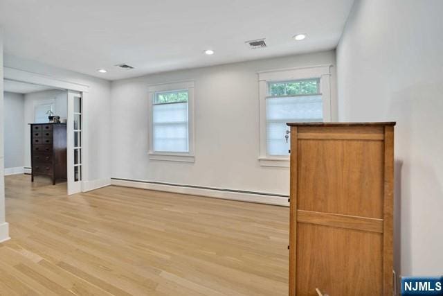 spare room with light wood finished floors, baseboard heating, a wealth of natural light, and recessed lighting