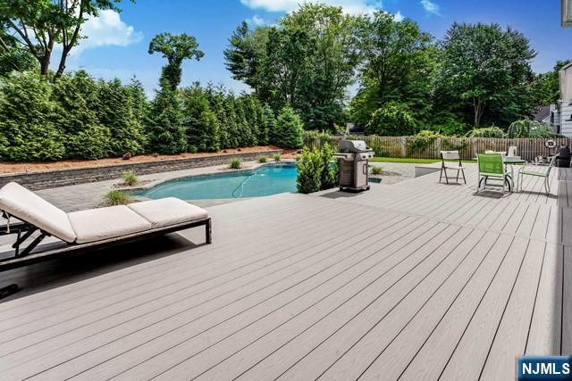 view of swimming pool featuring a deck, a fenced in pool, fence, and grilling area