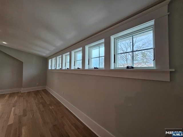 interior space with lofted ceiling, wood finished floors, and baseboards