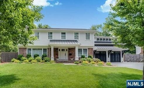 view of front of home with aphalt driveway, a standing seam roof, fence, and a garage