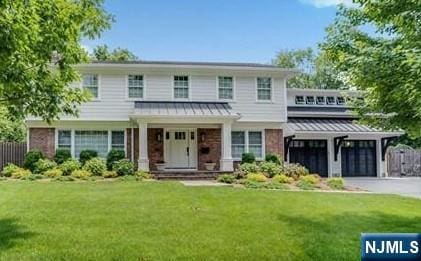 view of front of property with driveway, metal roof, a standing seam roof, a front lawn, and brick siding