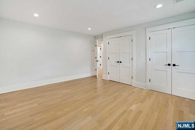 unfurnished bedroom with multiple closets, light wood-type flooring, baseboards, and recessed lighting