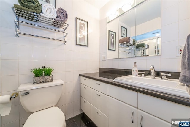 bathroom featuring vanity, tile walls, and toilet