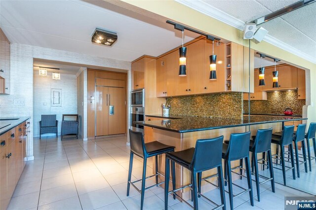 kitchen with backsplash, crown molding, light tile patterned floors, and built in appliances