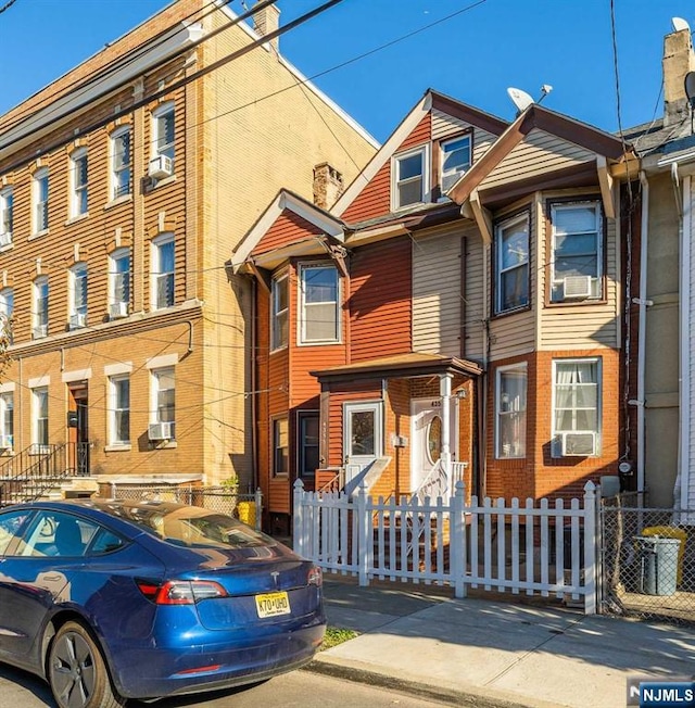 multi unit property with a fenced front yard, cooling unit, and brick siding