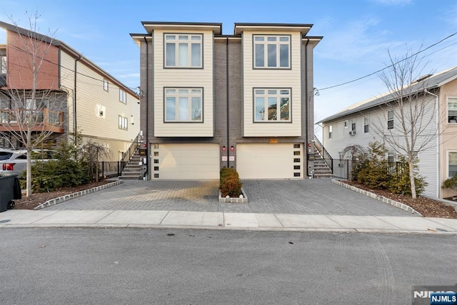 view of front of home with driveway, an attached garage, and stairs