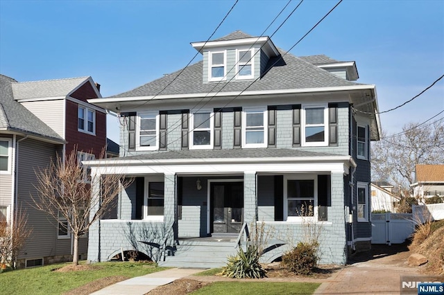 traditional style home with a porch and roof with shingles