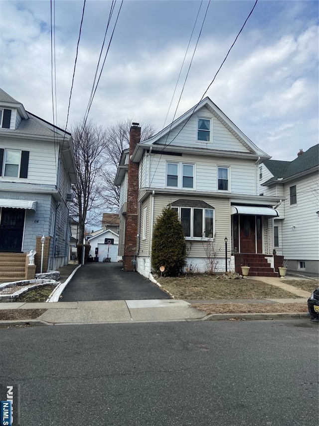 american foursquare style home with entry steps, driveway, and a chimney