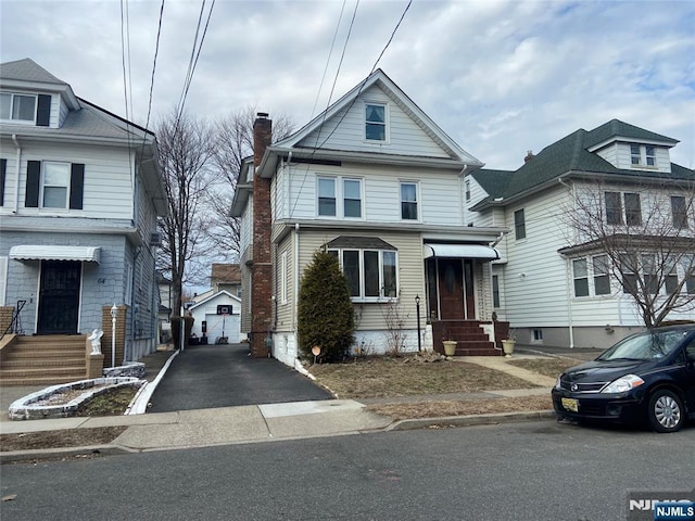 american foursquare style home with a chimney and aphalt driveway