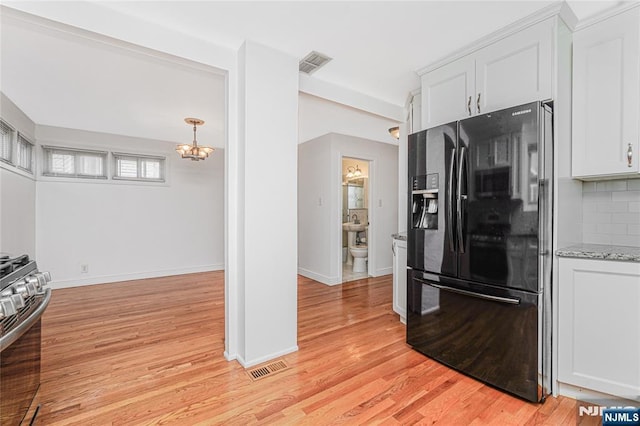 kitchen with visible vents, black fridge, backsplash, light wood finished floors, and gas range