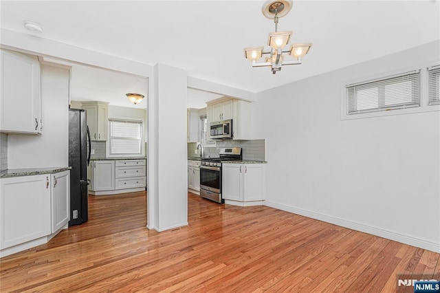 kitchen featuring a chandelier, appliances with stainless steel finishes, light wood-style flooring, and decorative backsplash