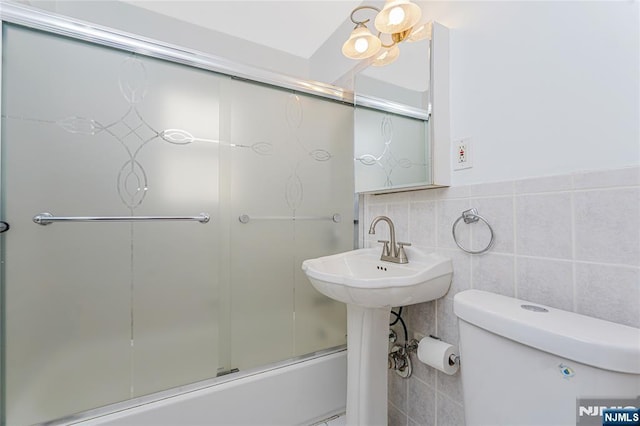 bathroom featuring a sink, toilet, and tile walls