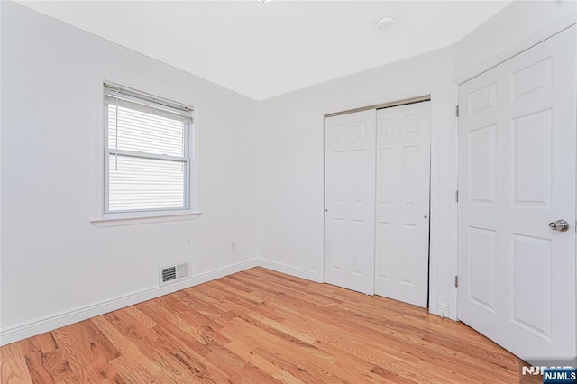 unfurnished bedroom featuring a closet, light wood-type flooring, visible vents, and baseboards