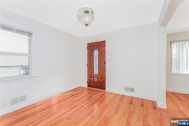 foyer featuring light wood-type flooring, visible vents, and baseboards