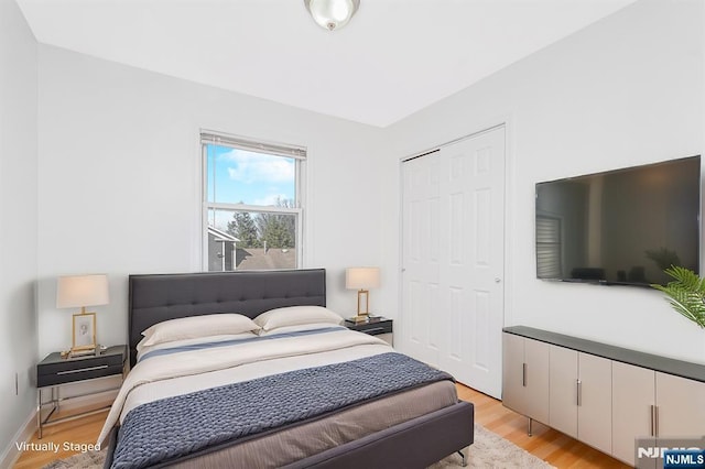 bedroom with light wood-type flooring, a closet, and baseboards