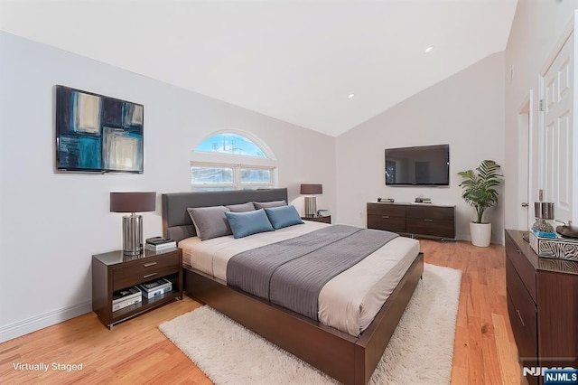 bedroom with high vaulted ceiling, light wood-style flooring, and baseboards