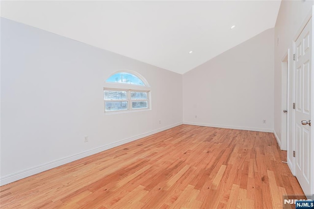 unfurnished bedroom with lofted ceiling, light wood-style flooring, and baseboards