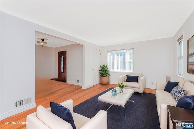 living area featuring baseboards, visible vents, wood finished floors, and ornamental molding