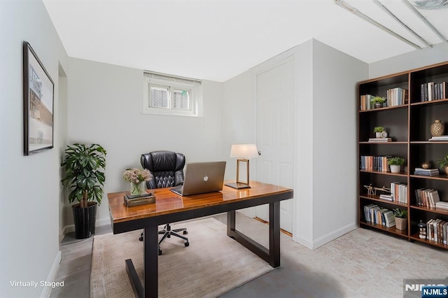 office area featuring concrete floors and baseboards