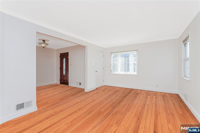 unfurnished room with light wood-style floors, visible vents, ornamental molding, and baseboards