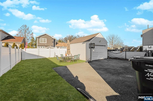 view of yard with an outbuilding, a fenced backyard, a garage, driveway, and a residential view