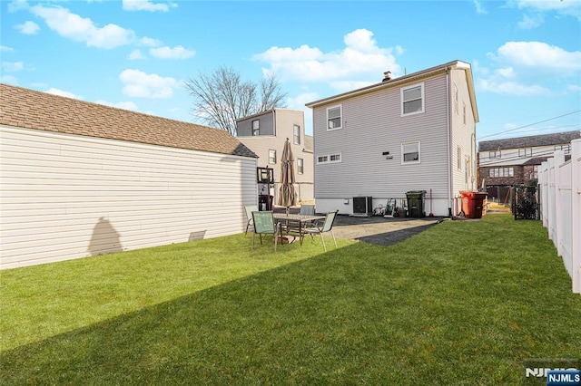 rear view of property featuring a fenced backyard, central AC, and a lawn