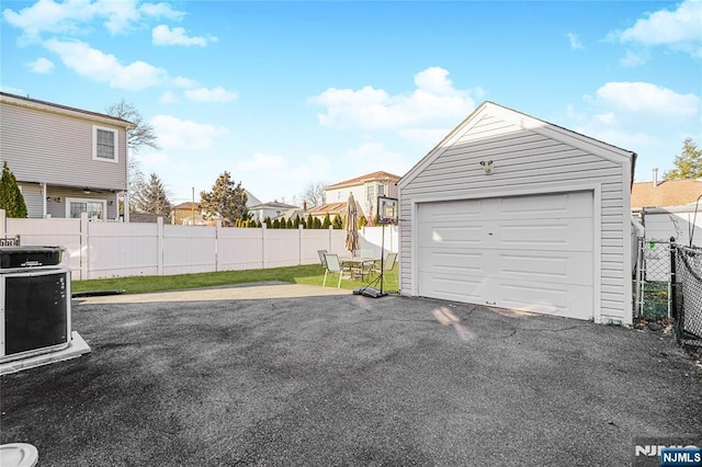 detached garage featuring a residential view, fence, and driveway