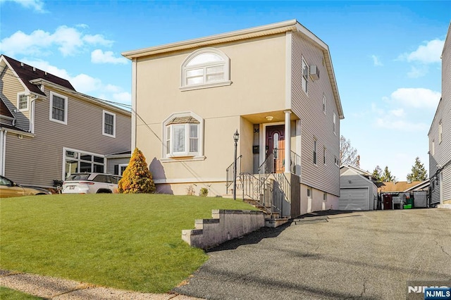 view of front of house featuring an outbuilding, a front yard, a garage, and stucco siding