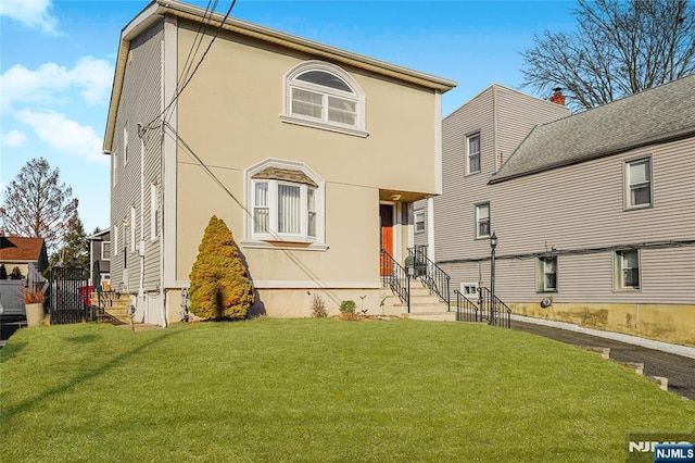 view of front of home with a front yard, fence, and stucco siding