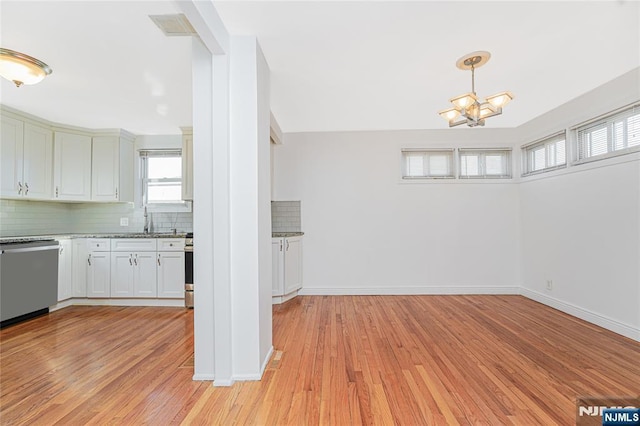 kitchen featuring light wood finished floors, stainless steel dishwasher, a sink, and tasteful backsplash