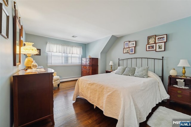 bedroom with a baseboard radiator, visible vents, and wood finished floors