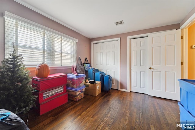 interior space with baseboards, visible vents, two closets, and wood finished floors