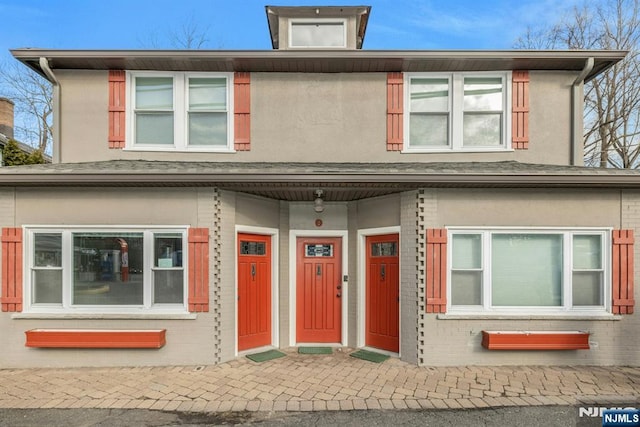 view of property featuring stucco siding and brick siding