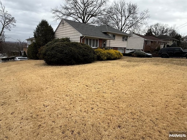 view of front of property with a front yard, brick siding, and roof with shingles