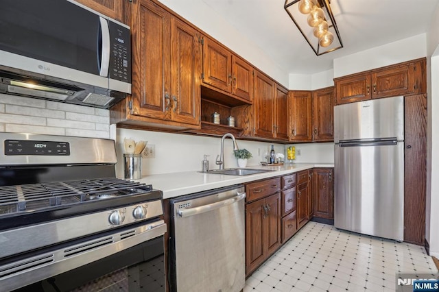 kitchen featuring stainless steel appliances, light countertops, a sink, and light floors