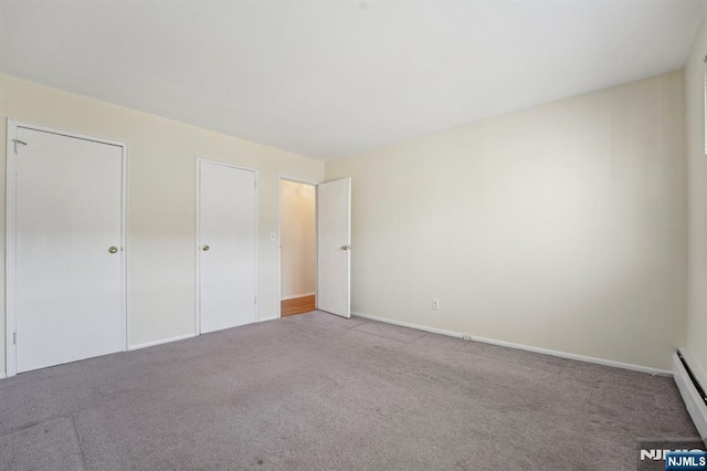 unfurnished bedroom with carpet floors and baseboard heating