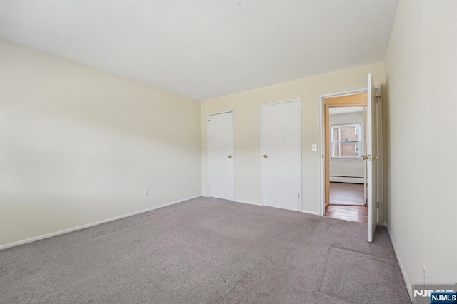 unfurnished bedroom with baseboards, a baseboard heating unit, and carpet flooring