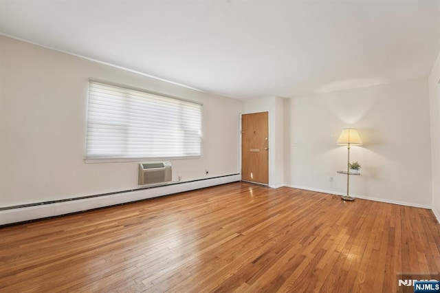 unfurnished living room with an AC wall unit, hardwood / wood-style floors, baseboard heating, and baseboards