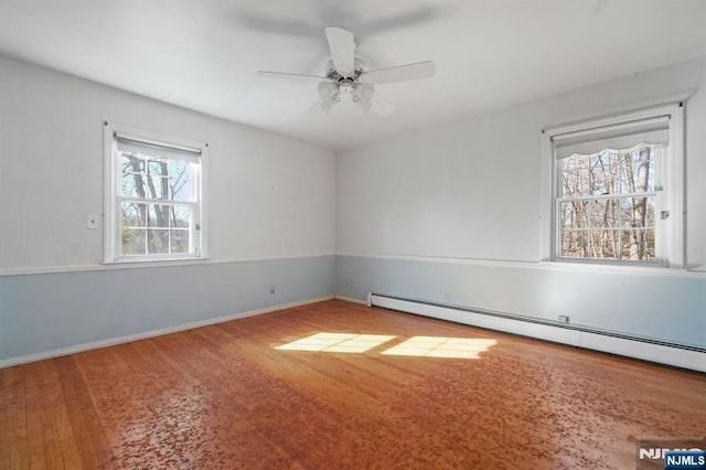 unfurnished room with baseboard heating, wood finished floors, a ceiling fan, and baseboards