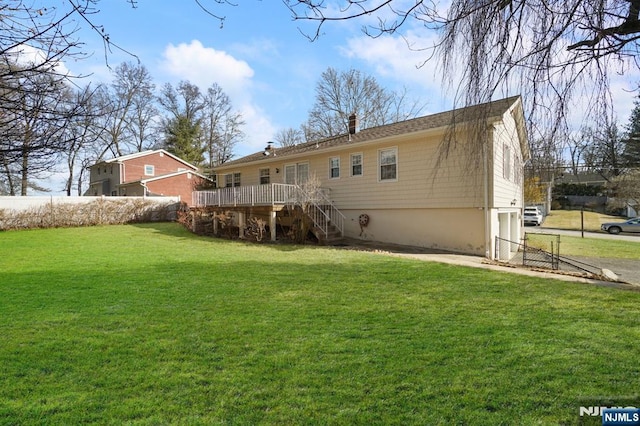 rear view of property with a yard, a chimney, fence, a deck, and stairs