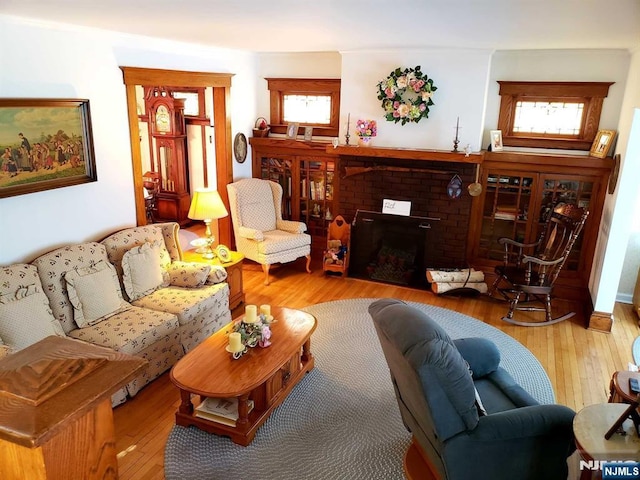 living room with a brick fireplace and hardwood / wood-style flooring