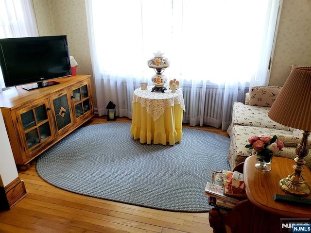 sitting room with light wood-style floors, a wealth of natural light, and wallpapered walls