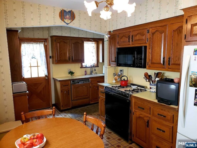 kitchen featuring light countertops, brown cabinetry, a sink, black appliances, and wallpapered walls